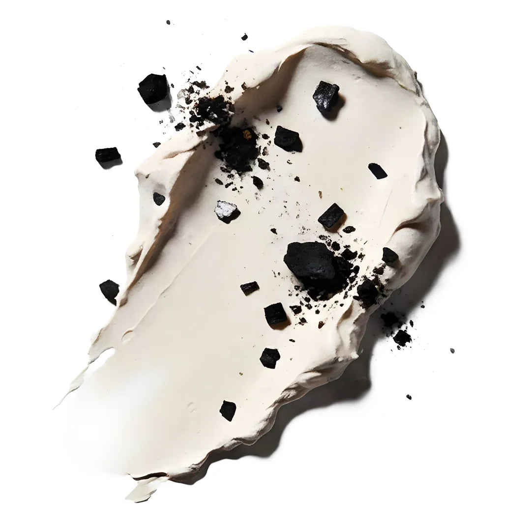 Top view of a clay texture with charcoal particles representing Yelf Spot Off Acne Cream with purifying ingredients