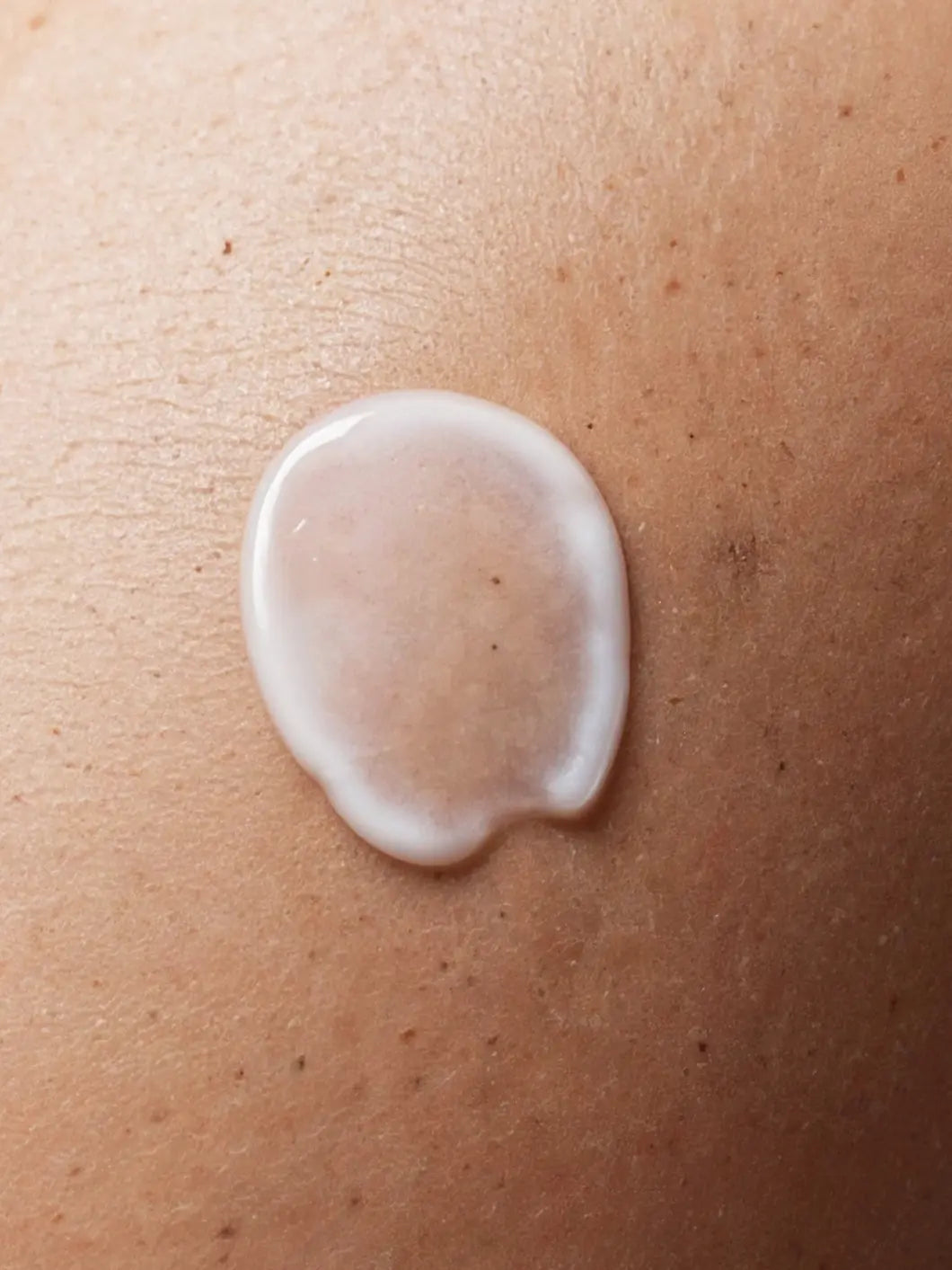 Yelf Spot Off Brightening Eye Cream – close-up of white fluid skincare texture on darker skin with visible pores