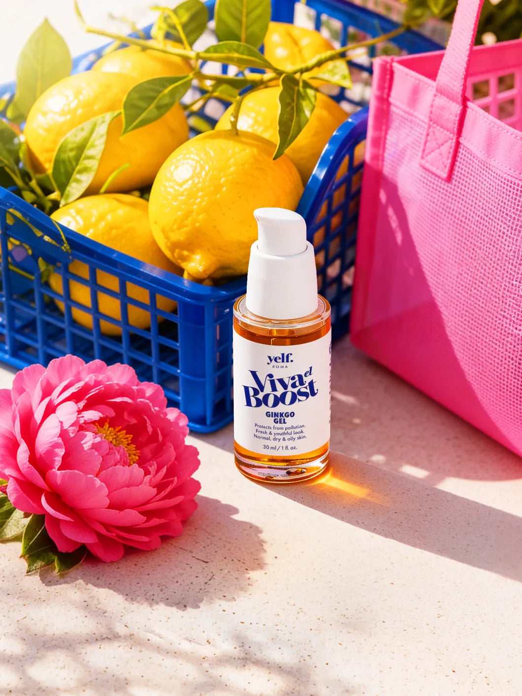 Yelf Viva el Boost Ginkgo Gel in a bright sunlit shopping scene with lemons in a blue crate, pink mesh bag and a magenta flower on a stone surface